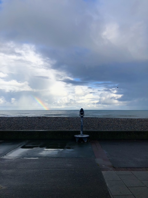 A view of the sea with a rainbow in the distance.