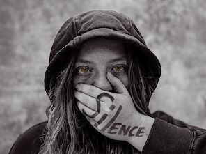 Girl in a hoodie covering her mouth with a hand labeled Silence